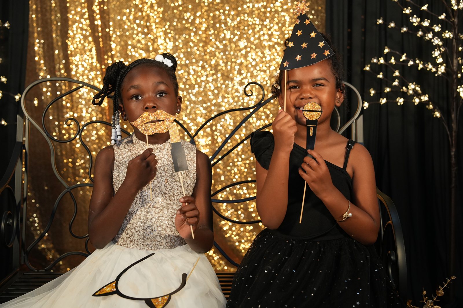 Two children in party dresses playing with photo props at the ball
