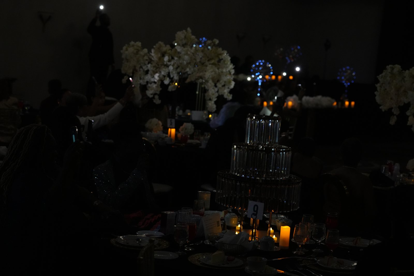 White floral centerpieces and candlelight on the banquet tables late in the evening