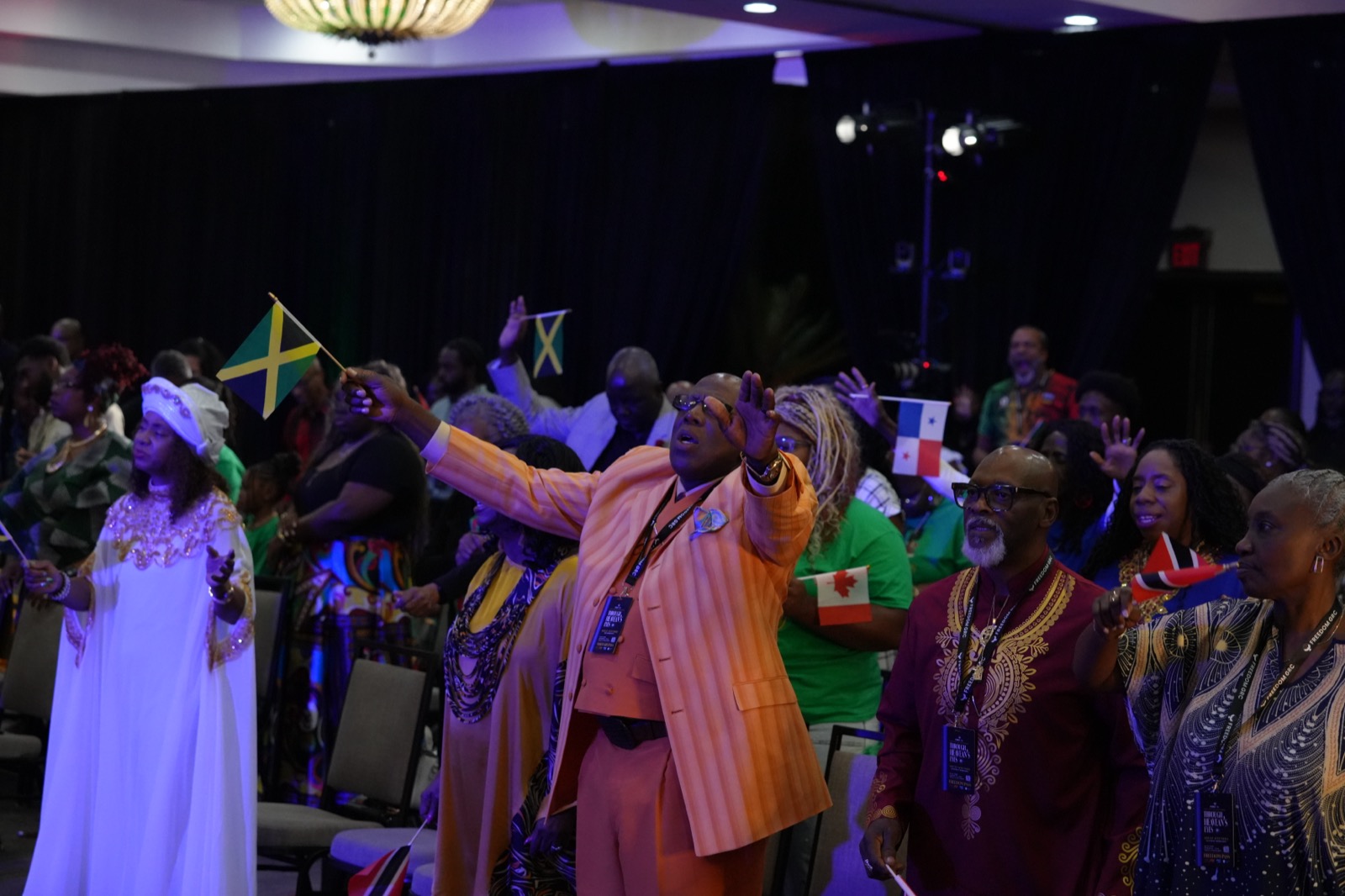 A multigenerational FreedomGRC congregation worships while holding national flags