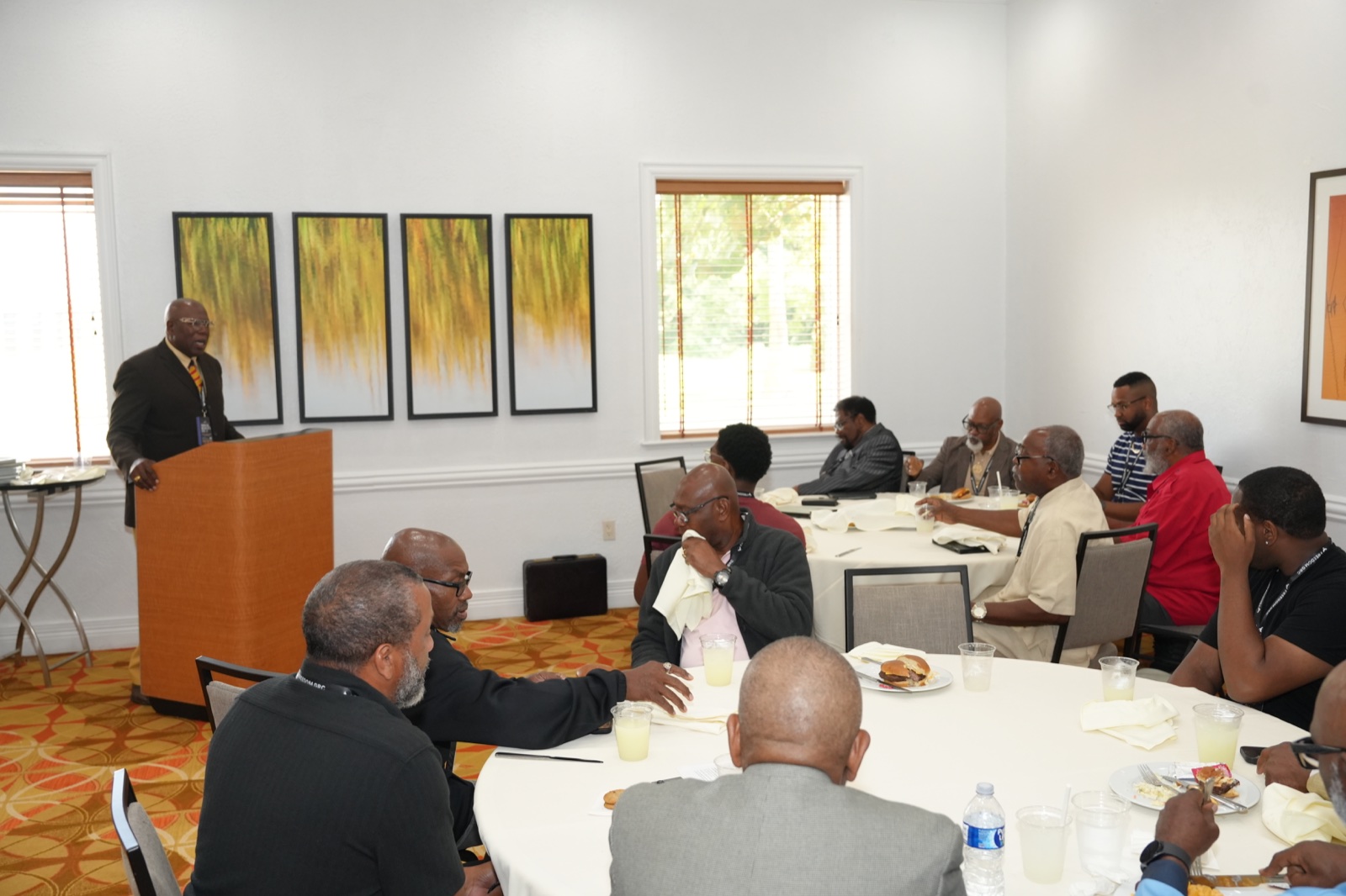 Men listen around luncheon tables during Gideon’s Band
