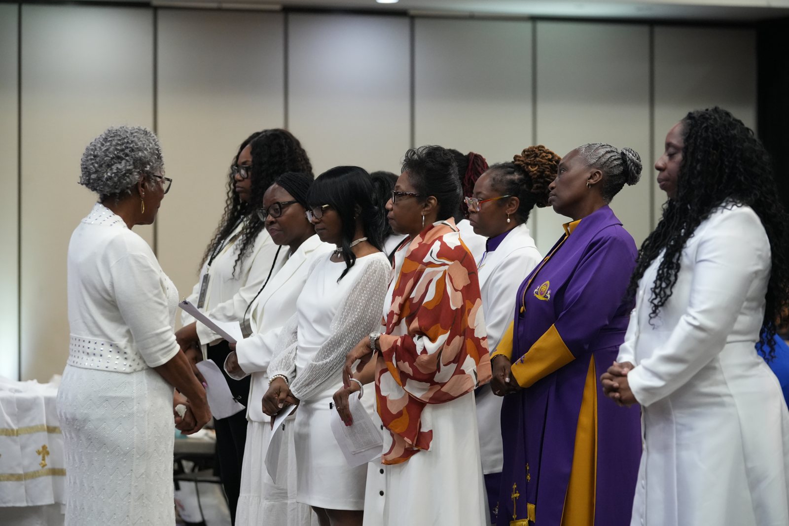 Five candidates dressed in white wait together before their ordination