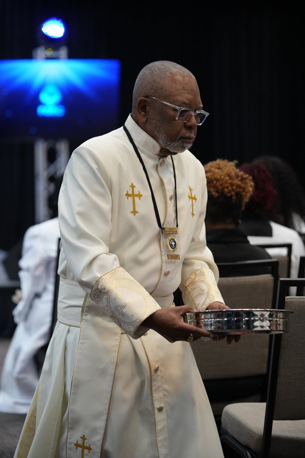 A minister carries the Communion vessels through the ballroom