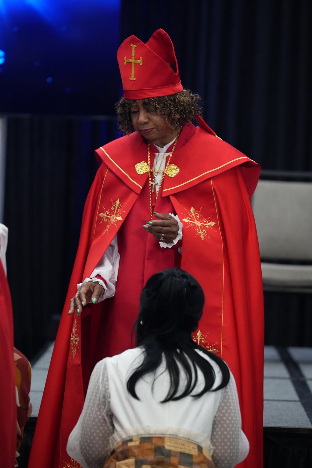 Chief Apostle Dr. Sandra Mitchell extends her hand in prayer over a kneeling ordination candidate