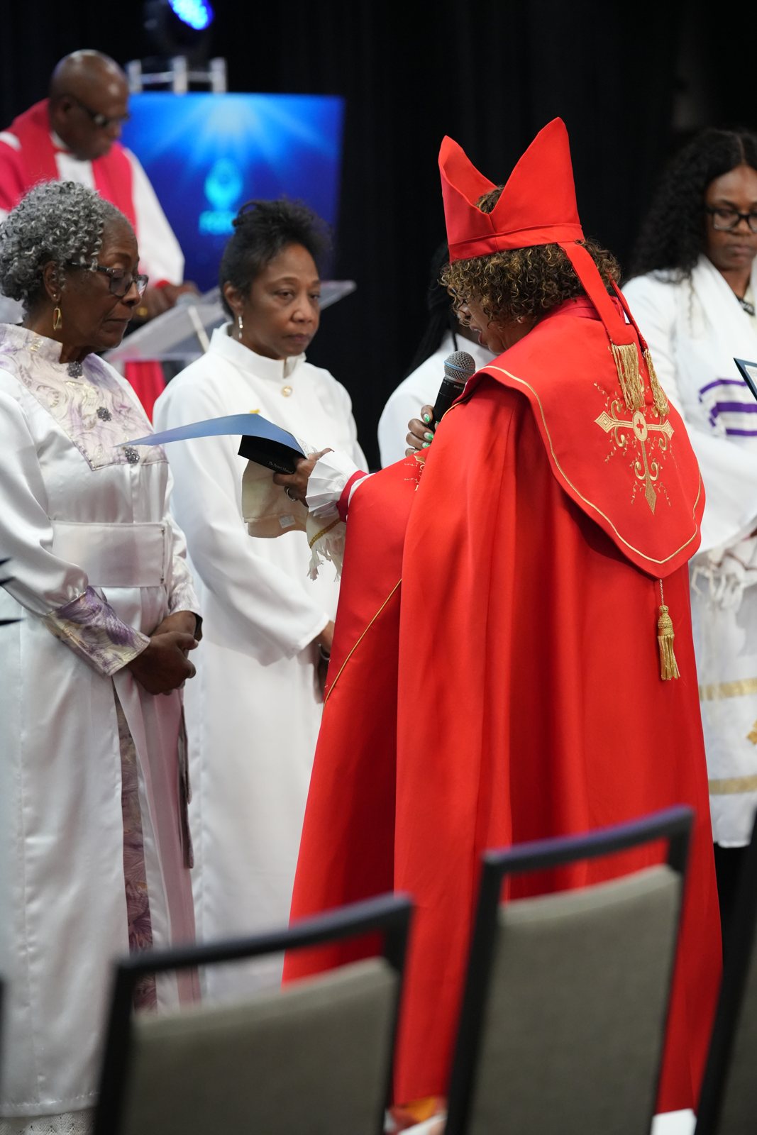 Chief Apostle Dr. Sandra Mitchell reads during the ordination service as clergy stand nearby