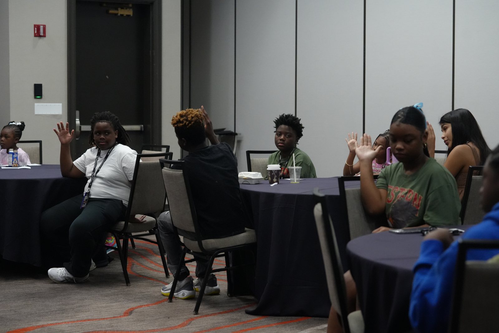 Young people raise their hands to answer during a youth session