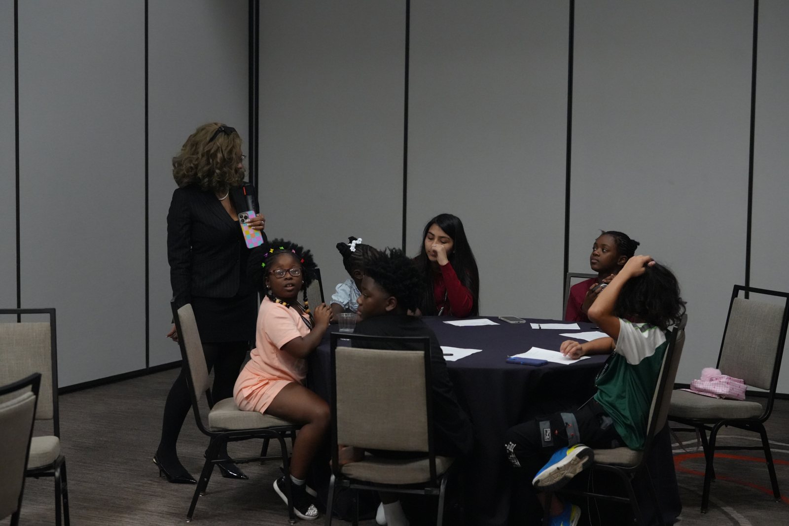 A facilitator works with younger children at a table during a youth session